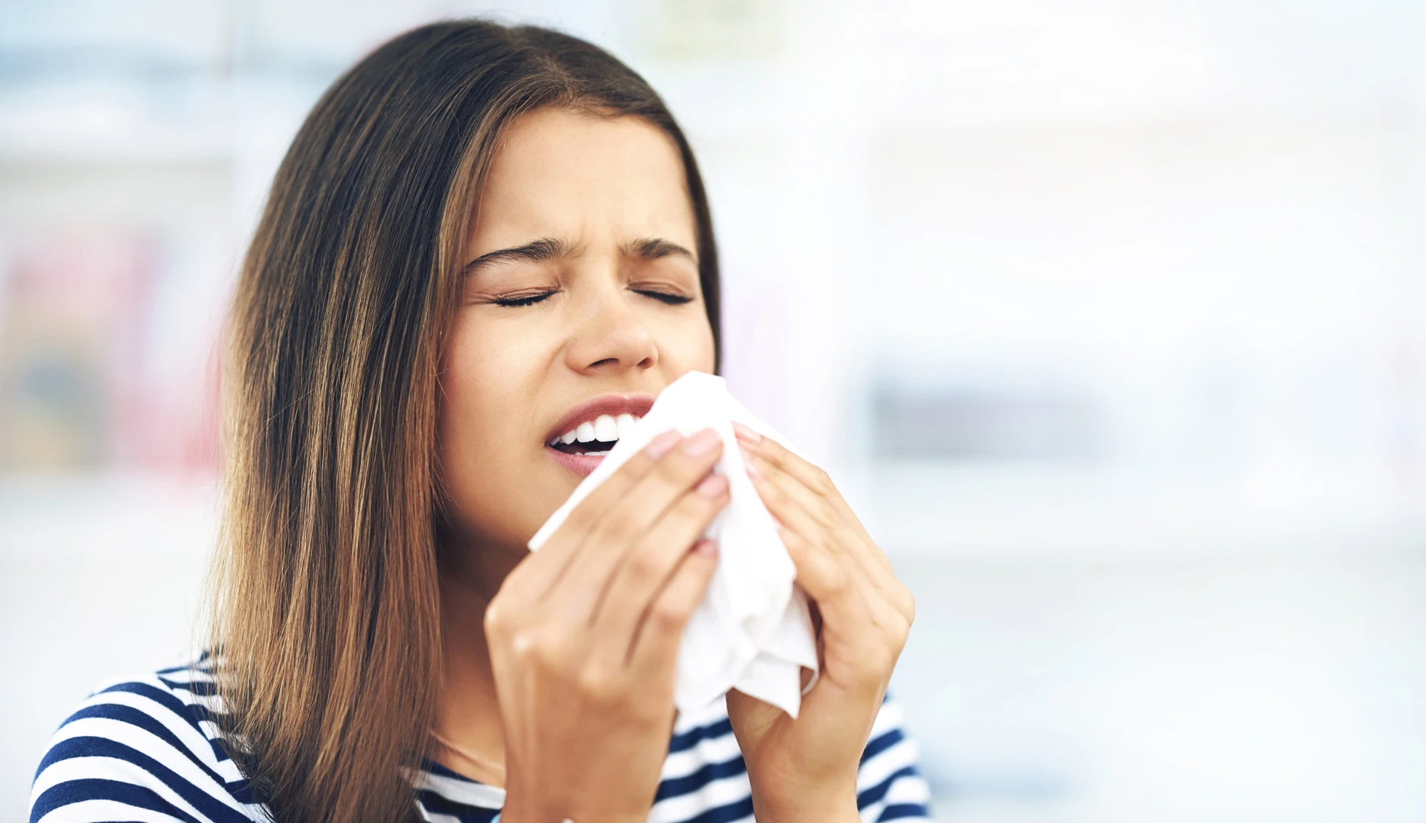 woman about to sneeze into a tissue from dust
