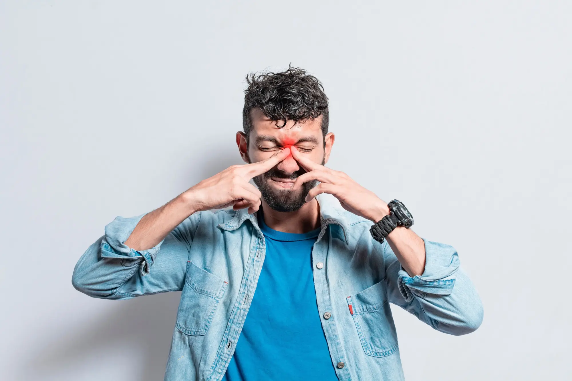 Man holding his nose with the area the sinuses are in highlighted in red