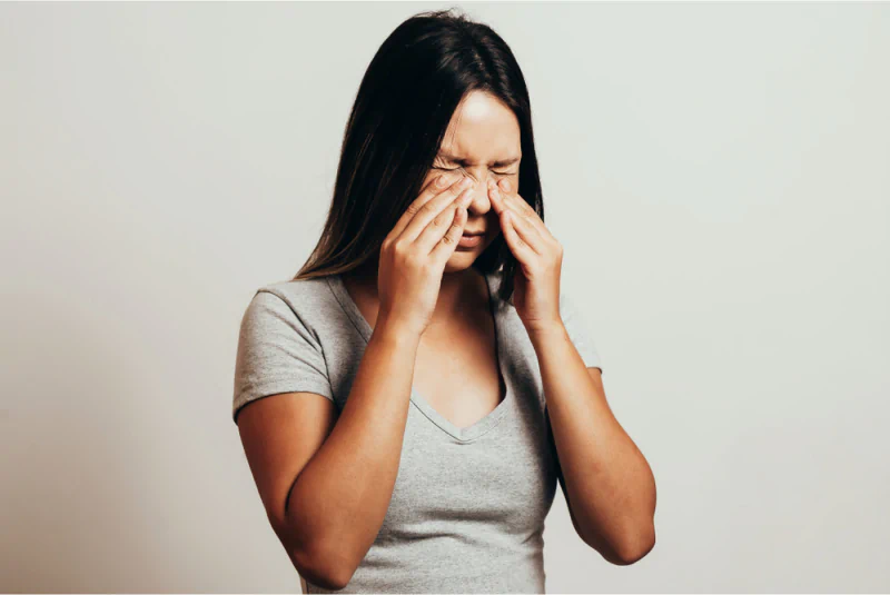 A woman with painful sinuses pressing her fingers to her face