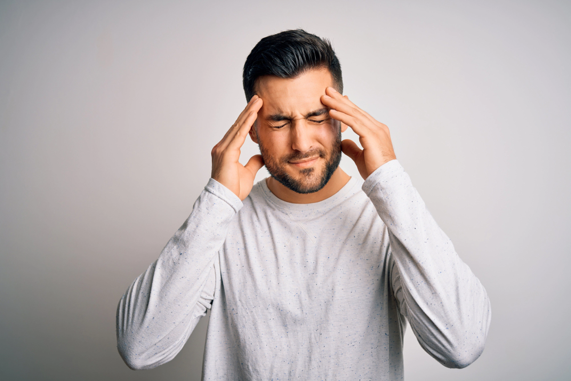 Young man holding his temples in pain.