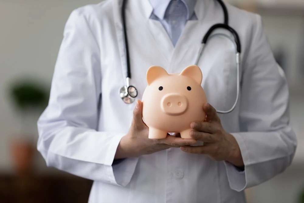 a physician holding a piggy bank