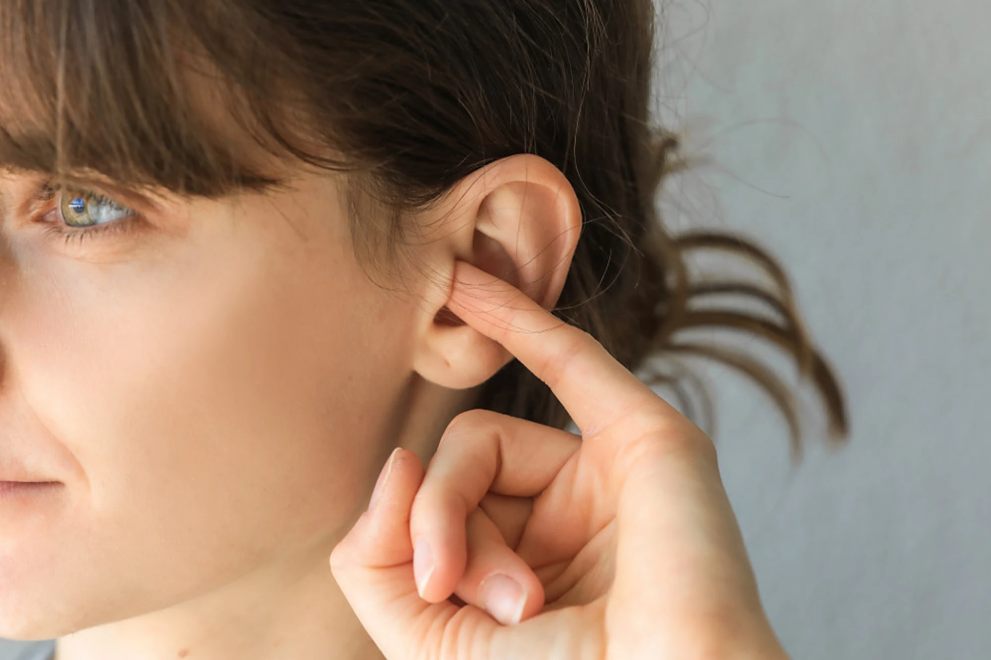 Woman putting her finger in her itchy ear