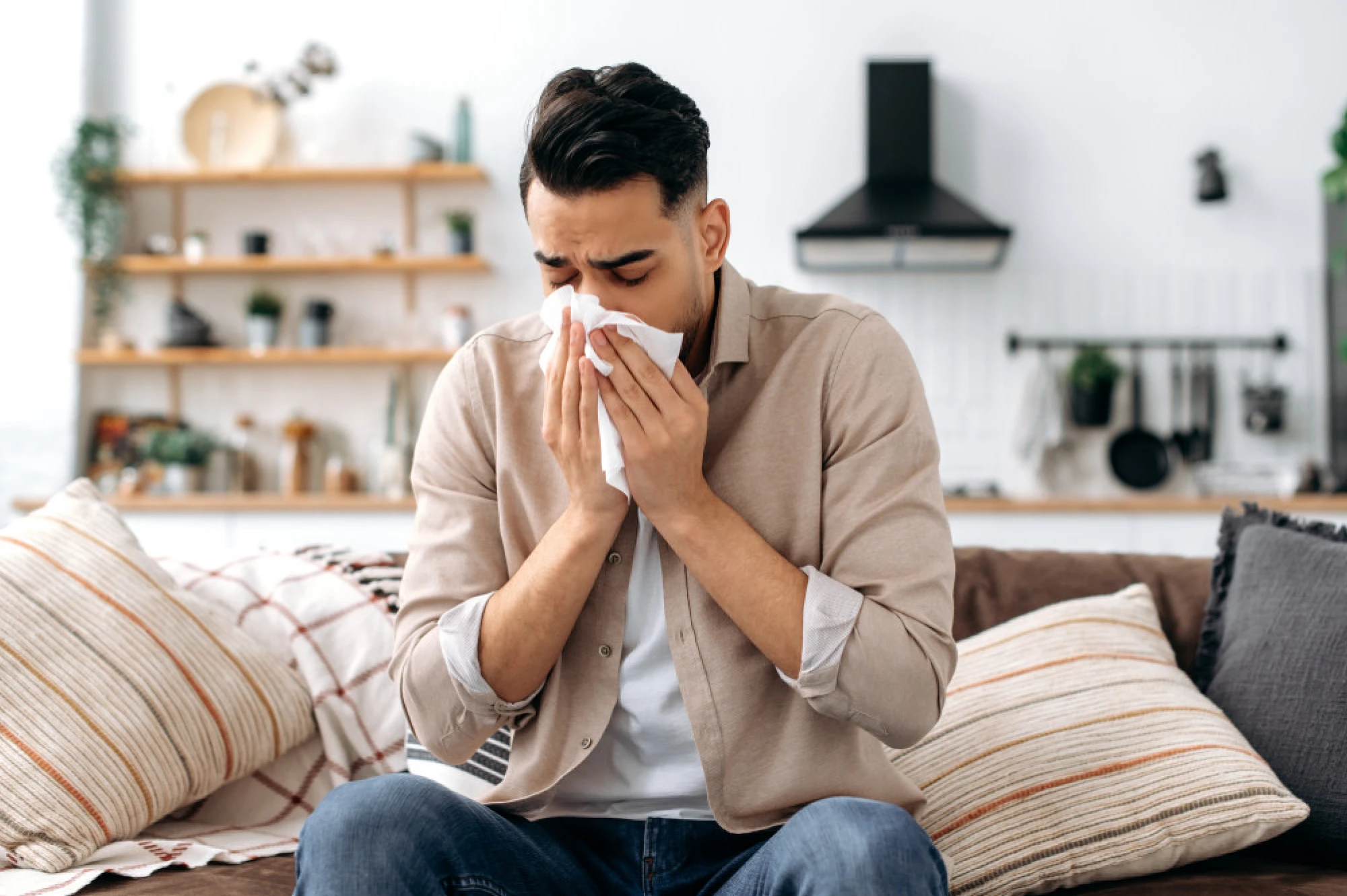 Man suffering with allergies blowing his nose into a tissue
