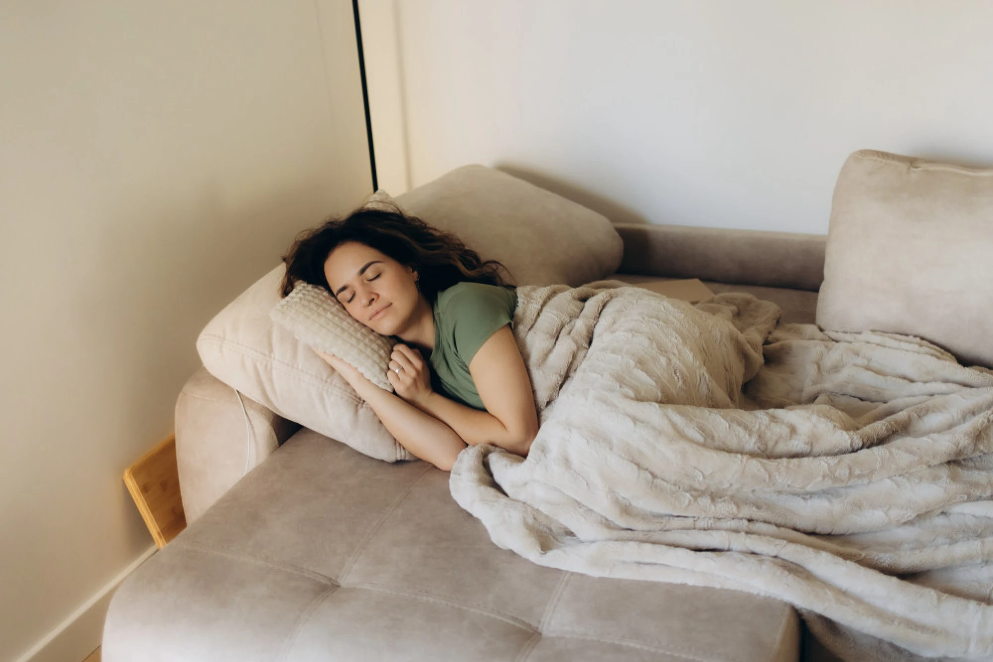 A woman laying on the couch, with her head on a pillow, recovering from balloon sinuplasty